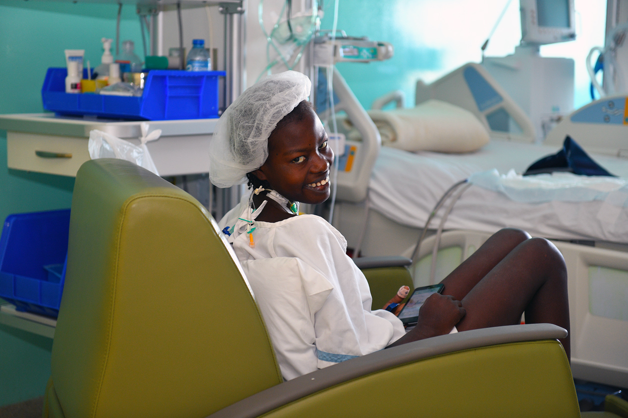 Wideline sits up smiling days after her mitral valve repair surgery.